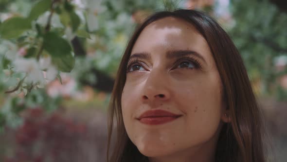 Close up of young woman looking around appreciating view of flower blossoms