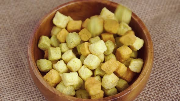 Dry vegetable cubes with herbs and dried plants falling in slow motion into a wooden bowl