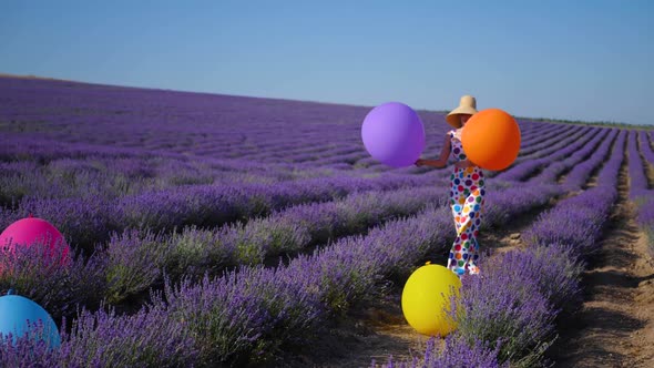 Woman in a Multicolored Suit with Circles and a Hat Holds Large Inflatable