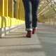 Women's Legs in Burgundy Boots and Blue Jeans Walk on a Closed Pedestrian Bridge - VideoHive Item for Sale