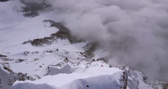 Aerial drone view of a skier skiing down a steep snow covered mountain