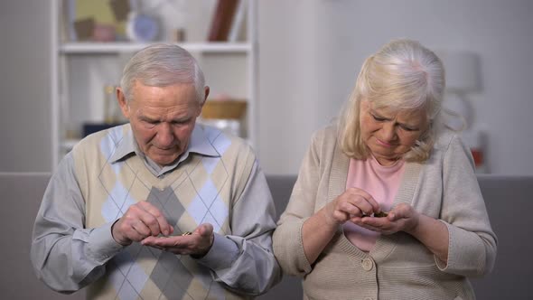 Depressed Old Couple Counting Coins in Open Palm, No Money for Living, Poverty