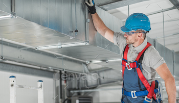 em Building. Caucasian HVAC Company Supervisor in His 40s Performing Final Ventilation Check.
