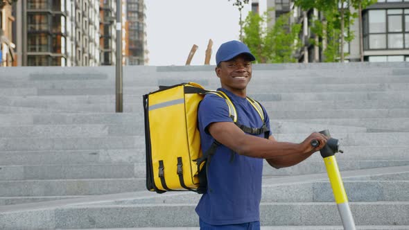 Portrait Smiling Afroamerican Man Courier with Backpack and Electric Scooter