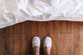 Male feet in white hotel slippers standing in front of the bed - PhotoDune Item for Sale