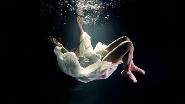 a Girl in a White Dress Under the Water Mysteriously Hangs in the Rays of the Sun As in a Fairytale