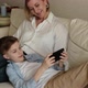 Teenager Lies on the Lap of an Adult Woman and Looks at the Phone - VideoHive Item for Sale