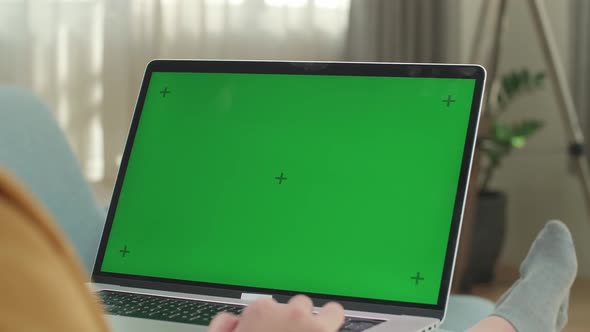 Asian Woman Sitting On Couch And Using Laptop Computer With Mock Up Green Screen Display