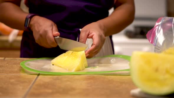 Black woman slicing bright yellow fruit into pieces, Closeup