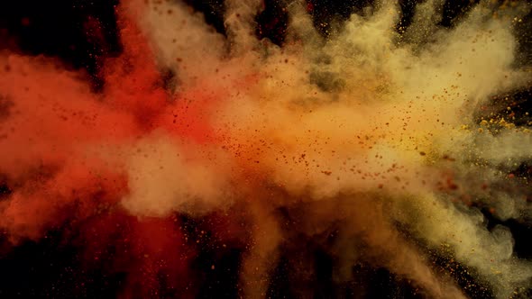 Colorful powder/particles fly after being exploded against black background. Slow Motion.