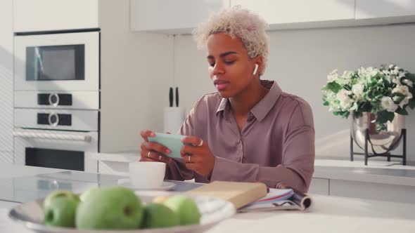 Smiling Young African Woman Using Phone Spend Free Leisure Time in Kitchen