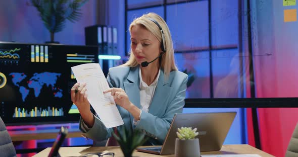 Businesswoman in Wireless Headset Sitting in front of Laptop During Video Meeting