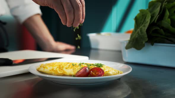 Professional kitchen of the restaurant, close-up: The chef sprinkles the finished omelet