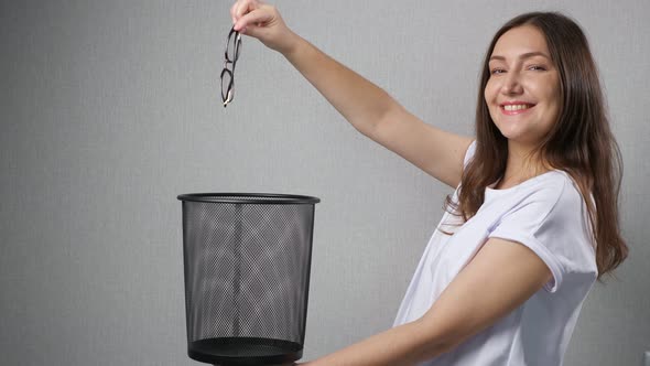 Happy Woman Throws Away Eyesight Glasses Into Trash Bin