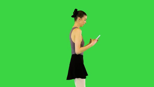 Young Ballerina in Training Clothes Walks with Mobile Phone in Hands Typing and Scrolling on a Green