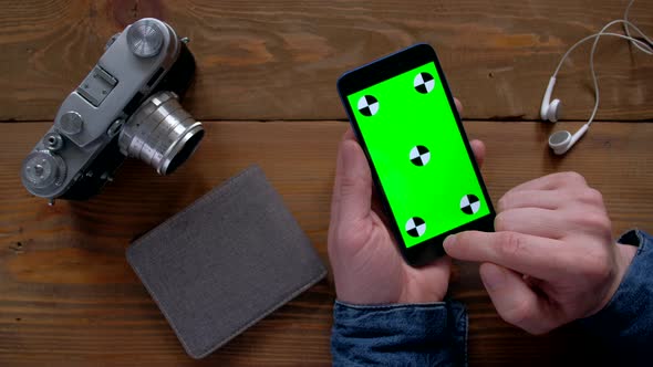 Male Using Smartphone  with Green Screen on Wood Table