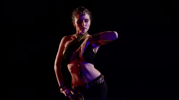 A Woman Dancing an Oriental Dance in a Studio on a Black Background Makes Beautiful Movements with