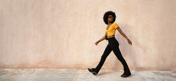 Smiling fashionable afro american woman walking on city street