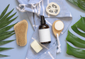 One pump glass bottle on blue bath towel near tropical leaves and skin care accessories, mockup - PhotoDune Item for Sale