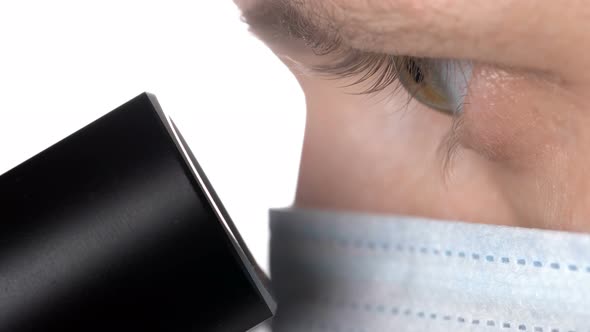 a Scientist Looks Through the Eyepiece of a Microscope