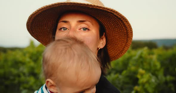 Portrait of Young Mom Gently Hugging Her Cute Little Baby Boy in French Provence Vineyard During