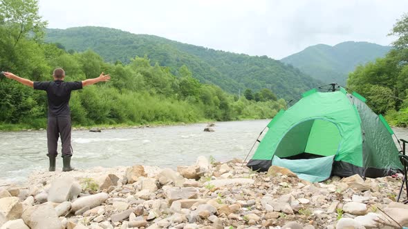 A Tourist Pitched a Green Tent Near a Mountain River