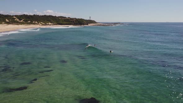 aerial shot of a surfer catching a right hand wave at pebbly beach