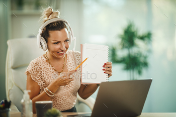 lone in her home office with headphones and working on laptop during COVID-19 pandemic.