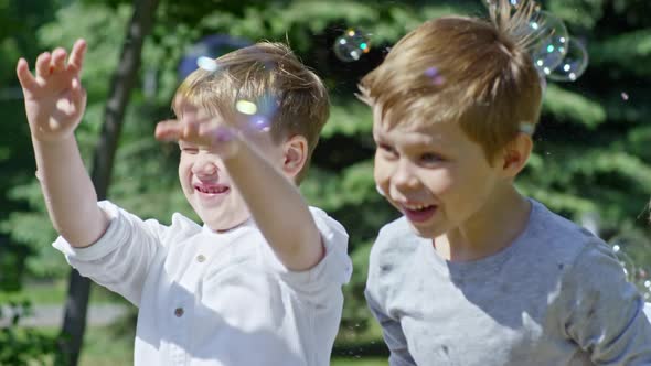 Kids Jumping and Popping Soap Bubbles Outdoors alt