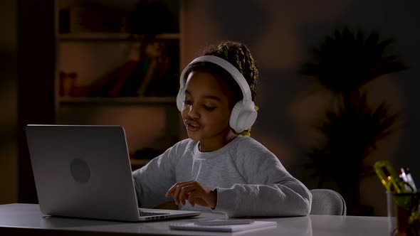 A Girl in White Headphones Listens to Music Singing Along with It Plays Online Games on Her Laptop