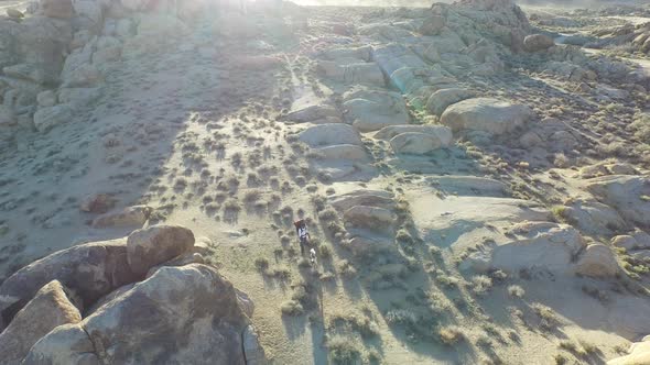 Aerial shot of a young man backpacking with his dog in a mountainous desert