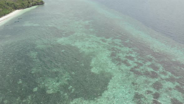 Aerial: Flying over tropical beach turquoise water coral reef Wakatobi Indonesia