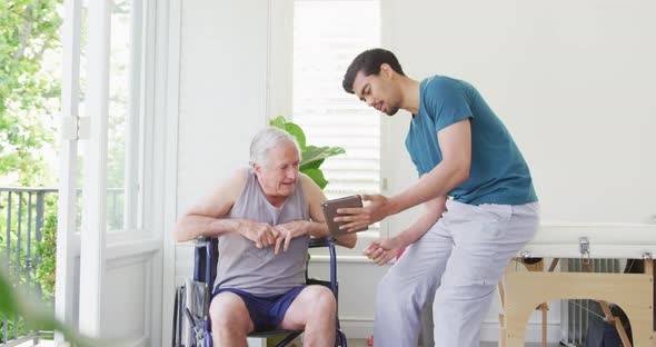 Male fitness coach discussing with disabled senior man on wheelchair in health club