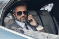 Confident mature businessman talking on mobile phone while sitting in the car - PhotoDune Item for Sale