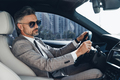 Confident mature man in formalwear and eyeglasses driving a car - PhotoDune Item for Sale