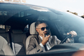 Confident man in formalwear using loudspeaker while talking on mobile phone from car - PhotoDune Item for Sale