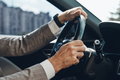 Close-up of man holding hands on steering wheel while driving a car - PhotoDune Item for Sale