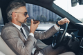 Mature man in formalwear using loudspeaker while talking on mobile phone from car - PhotoDune Item for Sale