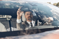 Confident man in formalwear adjusting rear view mirror while sitting on the front seat of a car - PhotoDune Item for Sale