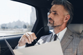 Mature businessman holding some document and looking thoughtful while sitting in the car - PhotoDune Item for Sale
