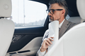 Mature businessman holding papers near face and looking thoughtful while sitting in the car - PhotoDune Item for Sale