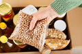 Plastic container with chickpeas in female hand on emergency food box background - PhotoDune Item for Sale