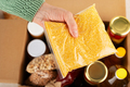 Plastic container with corn grits in female hand on emergency food box background - PhotoDune Item for Sale