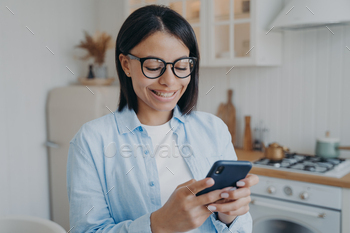 ng modern mobile apps, chat with a friend at home. Happy young female orders groceries for the kitchen in the online store or checks social networks.