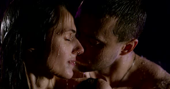 Portrait of a Passionate Beautiful Couple with Bare Shoulders, Which Are Under Heavy Rain on a Black