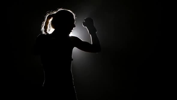 Woman Boxer Preparing for a Competition. Slow Motion. Black Background. Side View. Silhouette