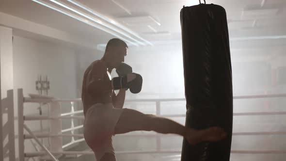Kickboxing, Athletic Man Fighter Trains His Punches, Beats a Punching Bag, Training Day in the