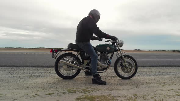 Low Aerial of Motorcyclist Kickstarting Motorcycle on California Coast Highway One