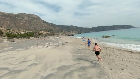 Group of young friends running and exercising Kedrodasos beach, Greece. FPV drone.