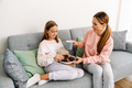 White mother and daughter drinking tea with cookies on sofa - PhotoDune Item for Sale